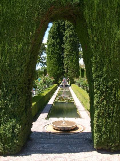 Ein Heckenbogen mit Sicht auf einen Brunnen